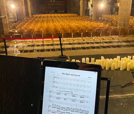 Sheet music titled 'The Show must go on' displayed on a tablet in front of empty theater seats.